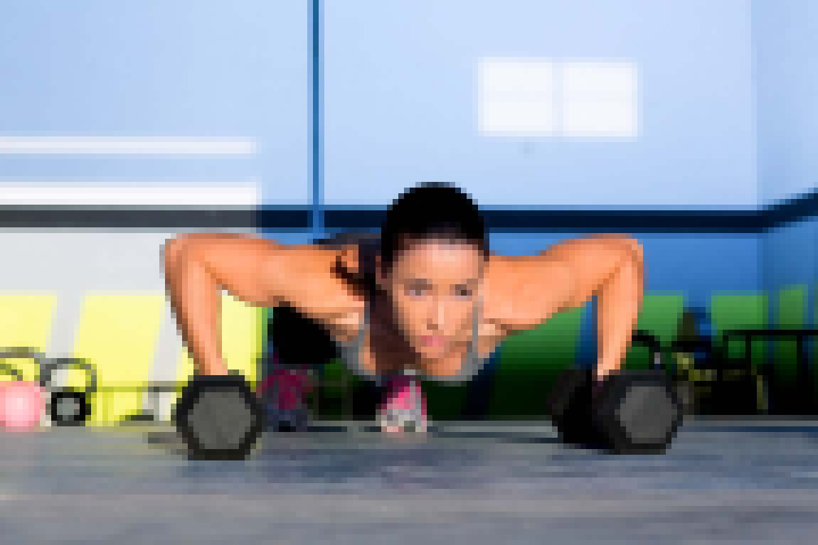 Gym woman push-up strength pushup exercise with dumbbell in a crossfit workout